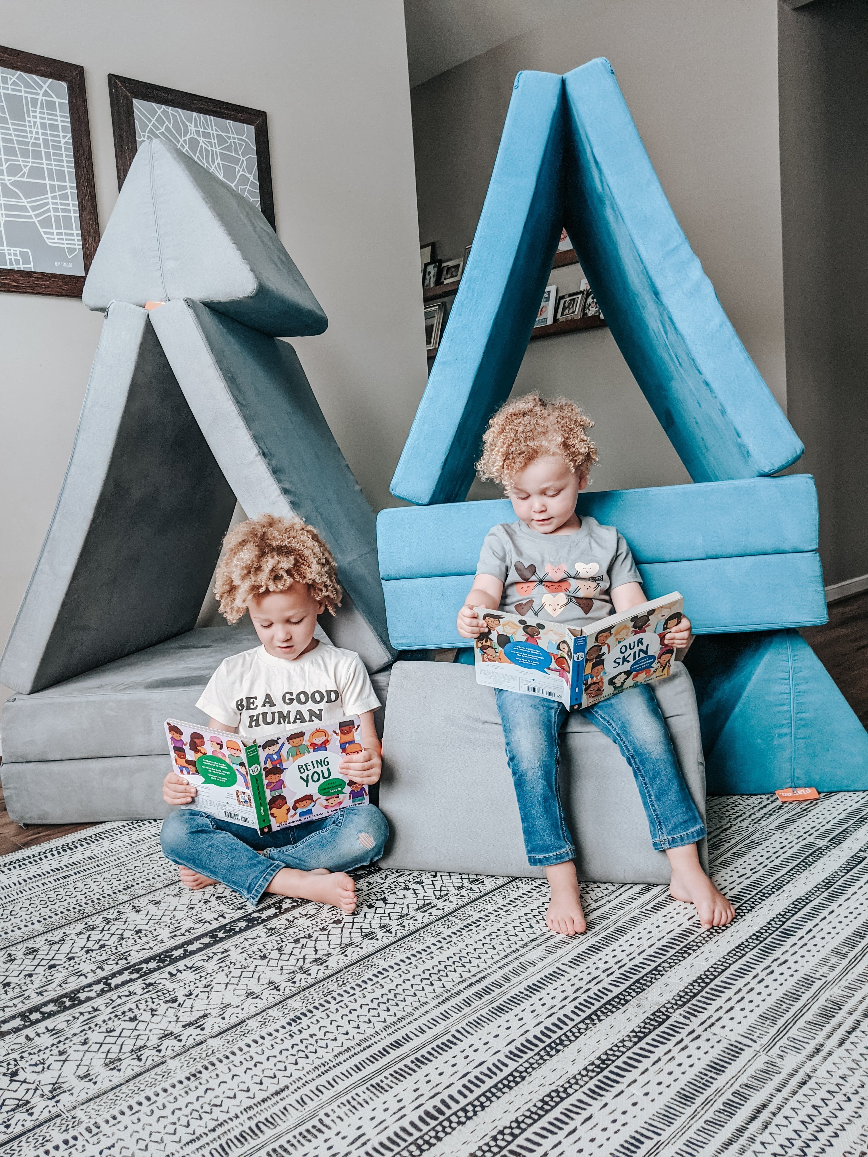 Two kids sitting in front of Nugget forts reading books