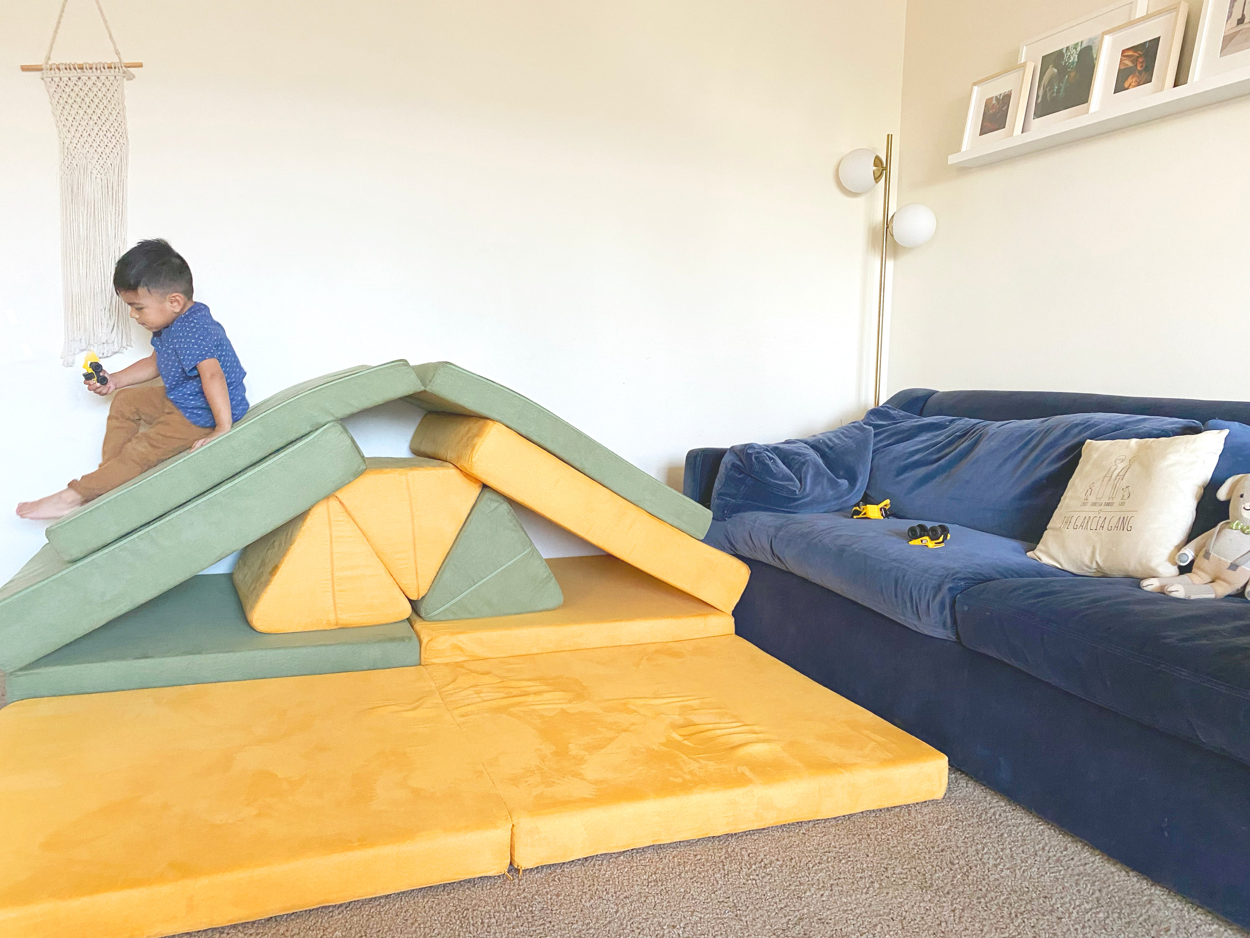 Child sliding down a two Nugget build, with a cushion placed over top of two ramp bases and pillows