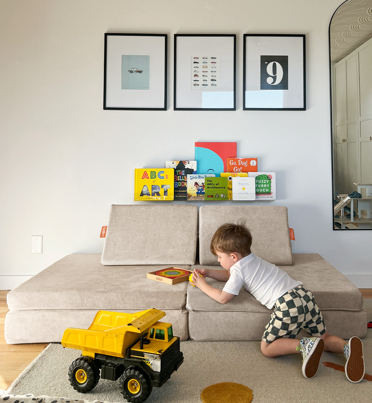 A child plays with a puzzle on a Dunebuggy Nugget surrounded by books and a yellow dump truck toy