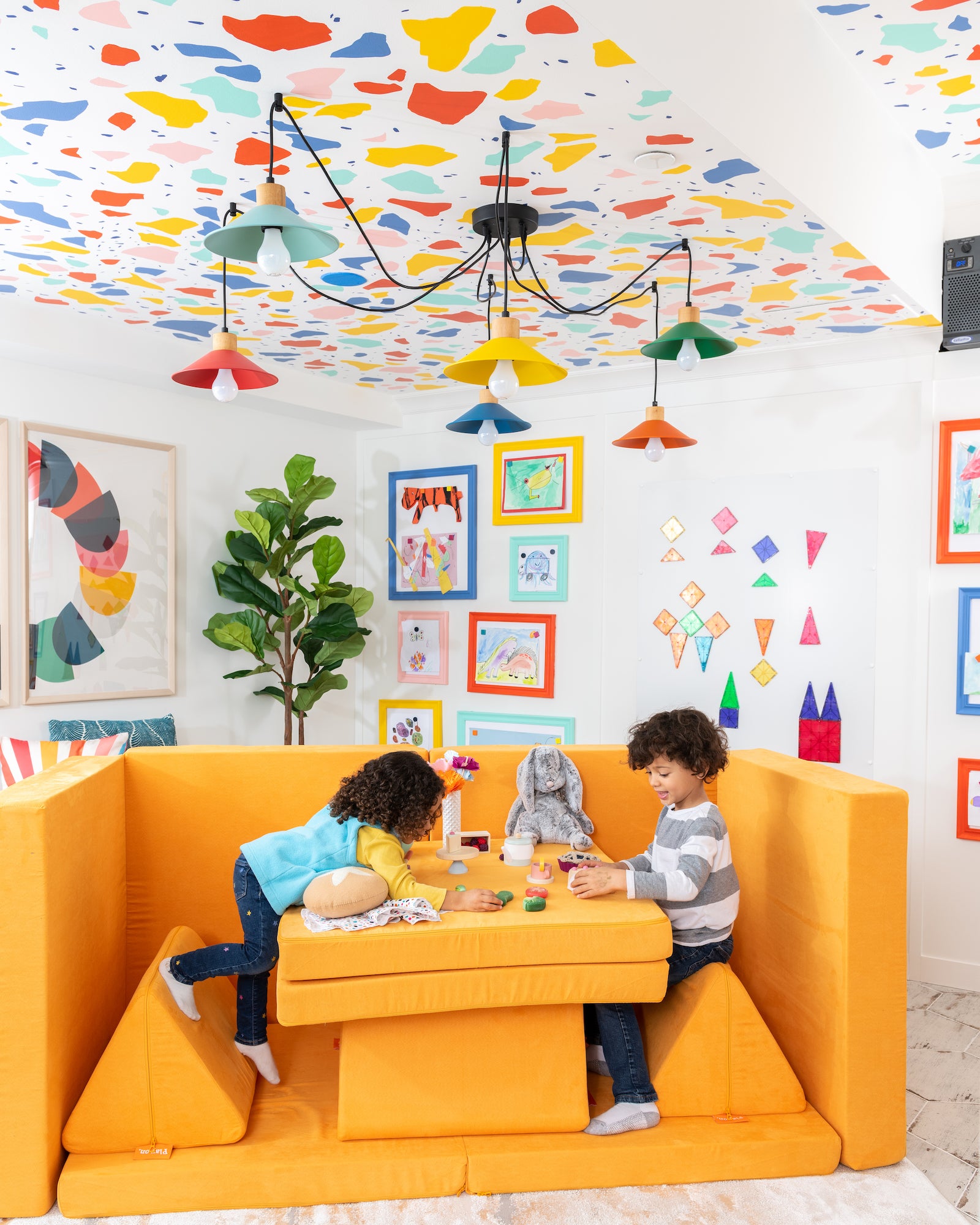 Two kids play restaurant at a Brightside Nugget set up as a table, with a colorfully decorated room as the backdrop.