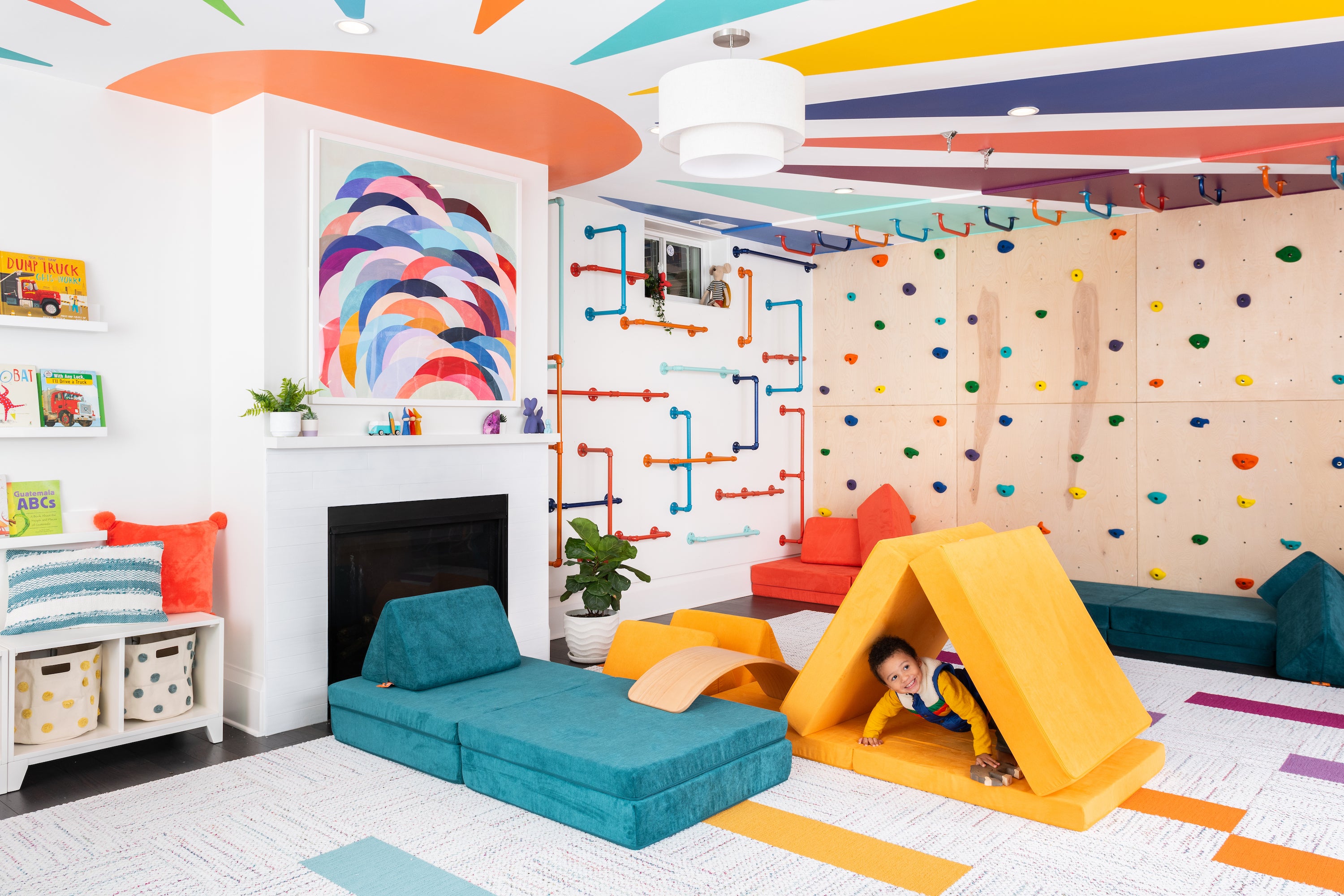 A brightly colored playroom featuring two Nuggets, a climbing wall, and accessible toy storage.