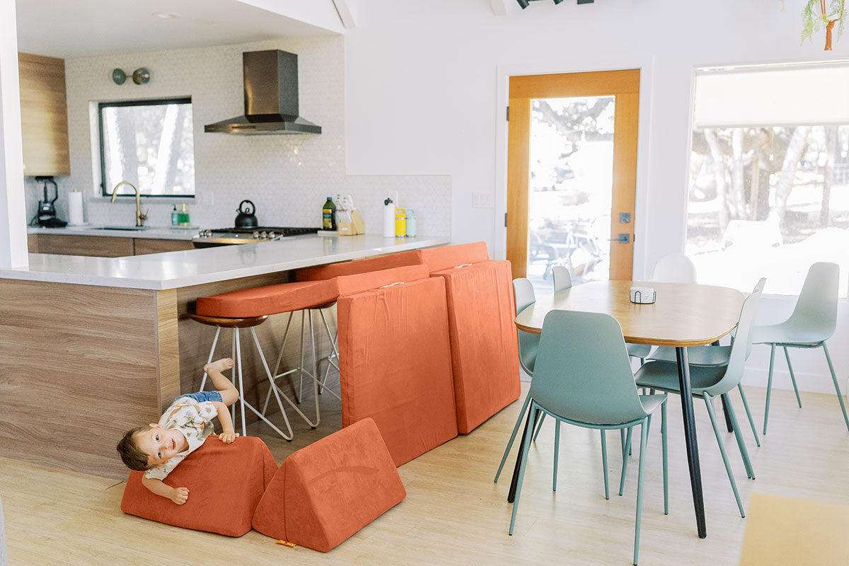 A child crawls through a Nugget tunnel made with a Rodeo Nugget and kitchen counter