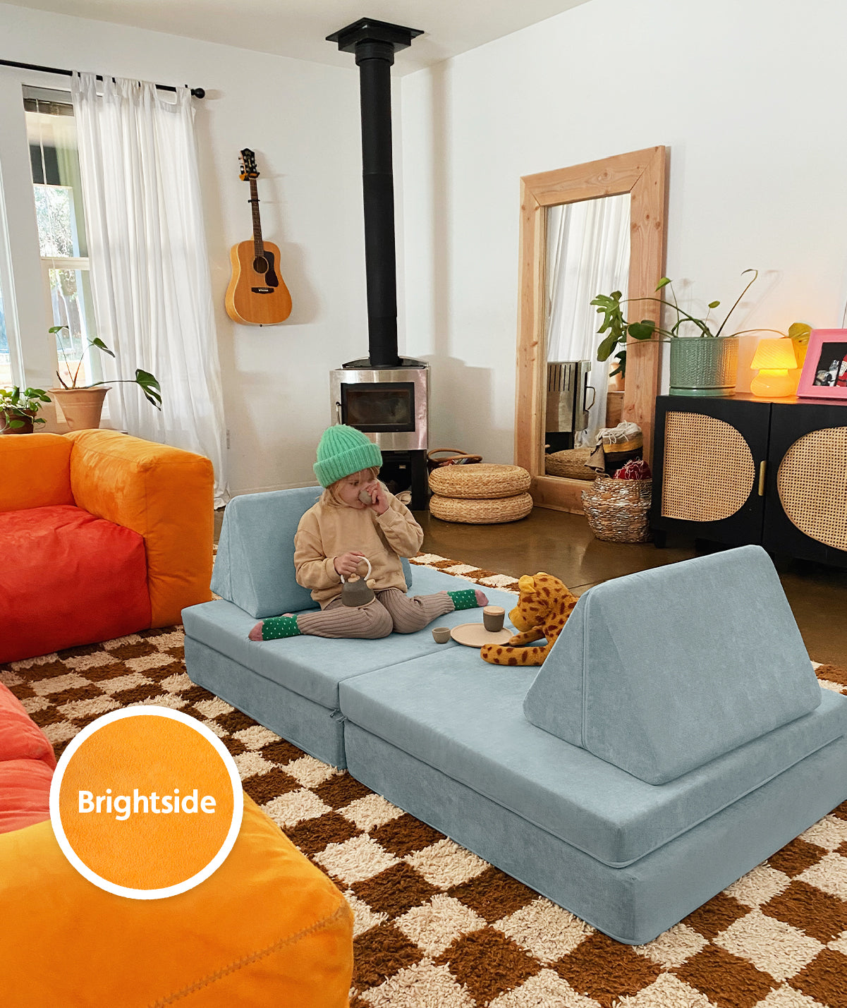 A child has a tea party in their living room on a Surfside Nugget surrounded by a orange couch. A Brightside color swatch is on the photo to show how it pairs with Surfside