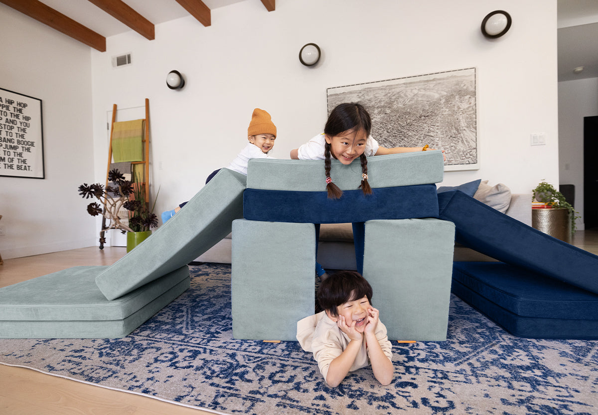 Three children play on a double slide build of two Nuggets in Surfside and Blueridge colors