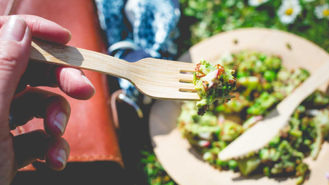 A person holding up a bite of their broccoli salad.