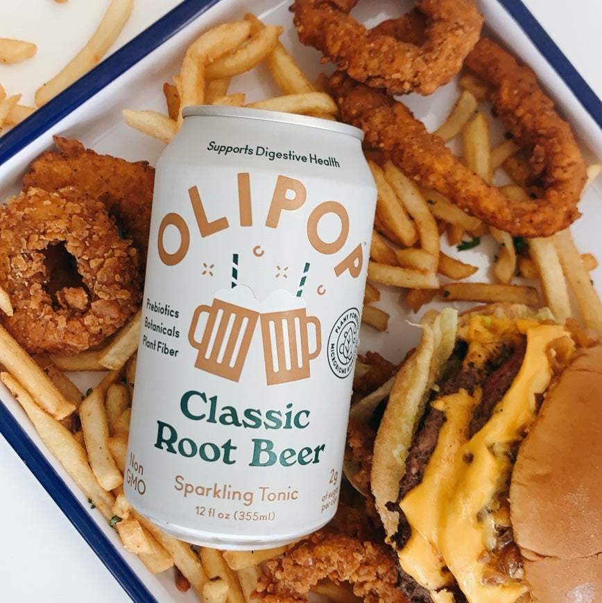 Olipop Root Beer's can over a dish of fish & chips and burger