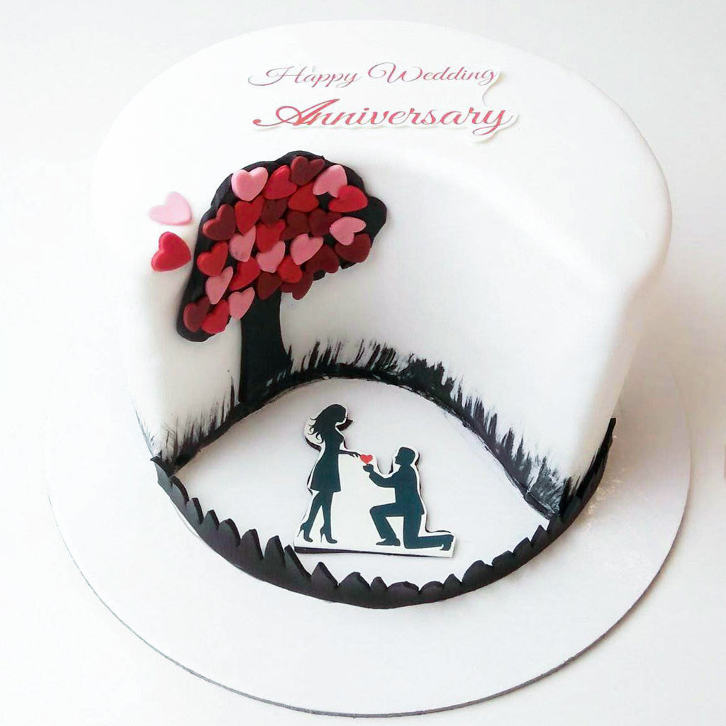 A cute cake for anniversary where caricatures of cute couple is kept on top  of cake – Creme Castle