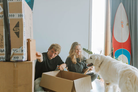 A couple with their dog unpacking boxes.