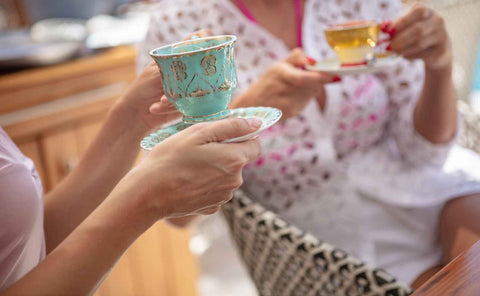 Two women enjoying afternoon tea in beautiful and colorful teacups