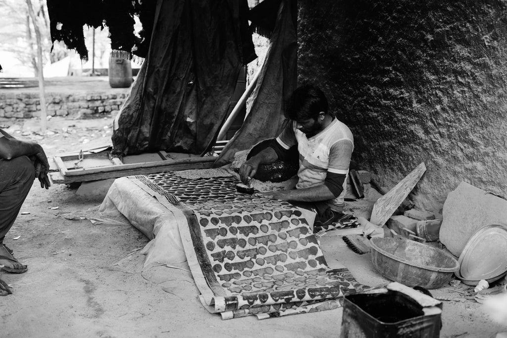 black and white photo of an indian craftsman block printing a traditional cloth