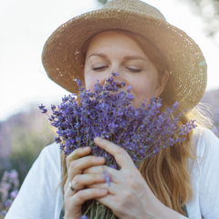 woman holding bouquet of lavender and smelling it 