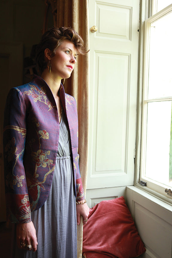 Young woman with short brown hair in a grey blue maxi dress with a curved collar Anya jacket in imperial blue.