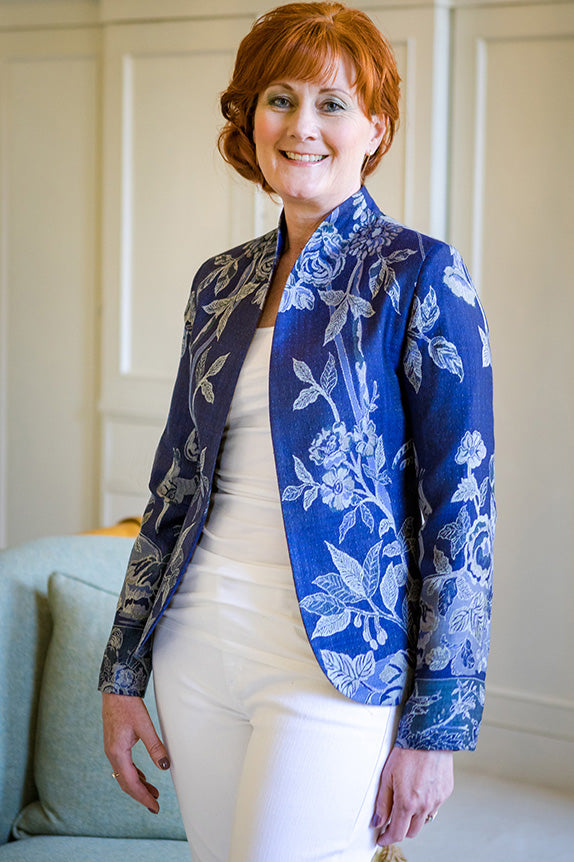 Older redhead woman in white jeans and tshirt with deep navy blue cashmere Anya jacket with floral pattern