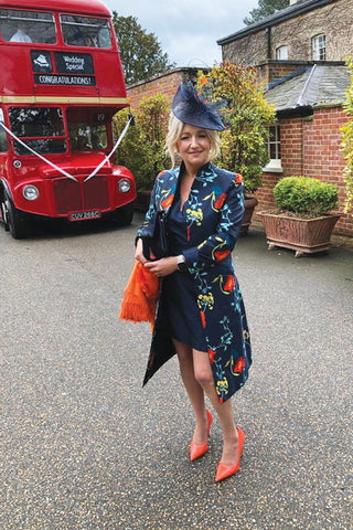 Mother of the bride wearing a silk long coat, the lyra coat in Poppy