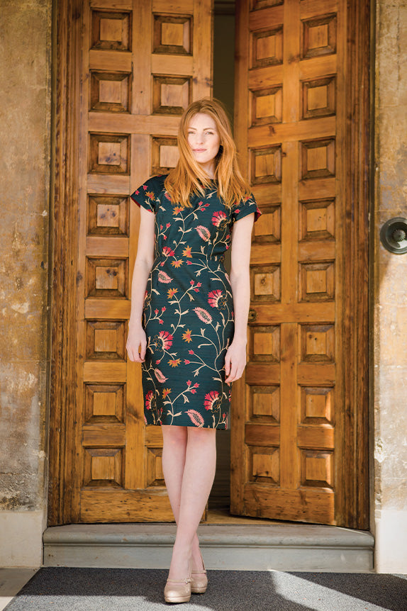 Red head woman in teal floral shift dress infront of wooden doors, shibumi hepburn dress in Mineral