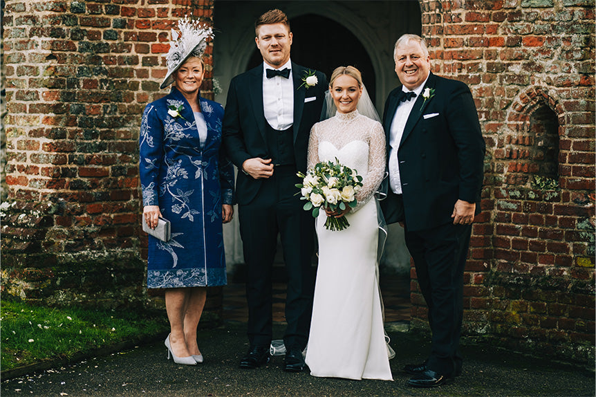 Mother of the groom in blue lyra coat with bride, groom and father of the bride.