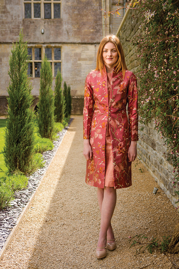 Redhead young woman in pink shalimar avani coat in walled garden