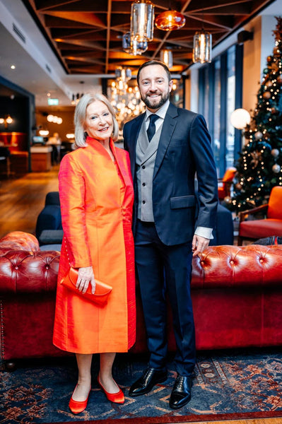 Mother of the groom in silk Shibumi orange coat.  Groom in dark suit.