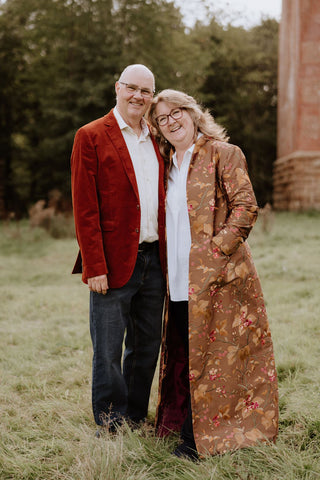 Woman, with husband, wearing a full length brown embroidered silk coat