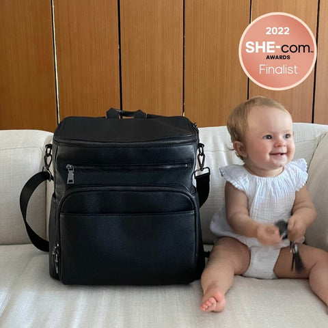 Ben & Ellie Baby Vegan Leather Nappy Bag on a Lounge Next to a Small Toddler