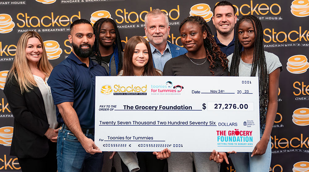 Members of Stacked Pancakes with executive director of Grocery Foundation, Shuan McKenna, holding a cheque