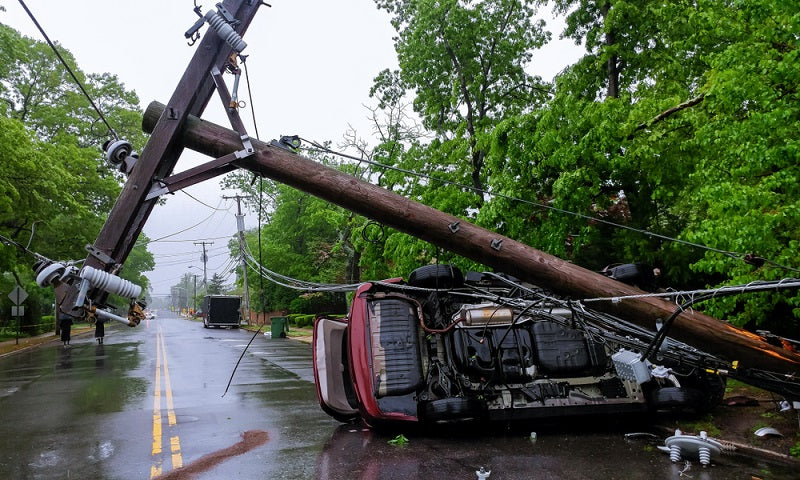 Car wrecked by crashed electric pole after a severe storm
