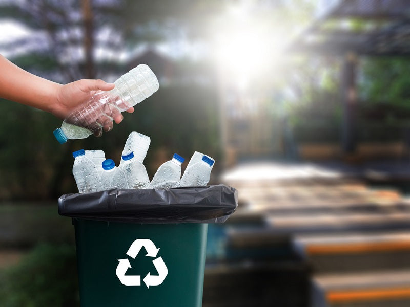 man hand putting plastic bottlen in recycle container