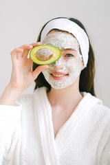 Woman applying an avocado face mask