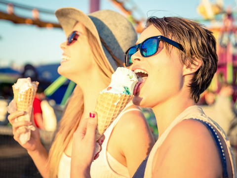 2 women wearing sun glasses while eating ice cream