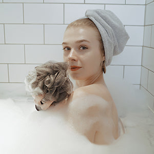 woman wearing hair wrap and holding shower pouf