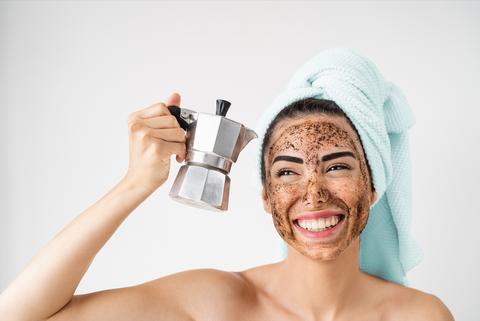 woman with coffee grounds on her face holding a moka pot