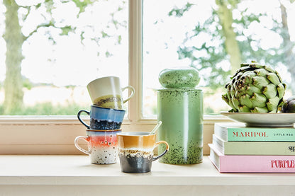 kiwi green stoneware storage jar with lid on a stack of books next o Americano mugs