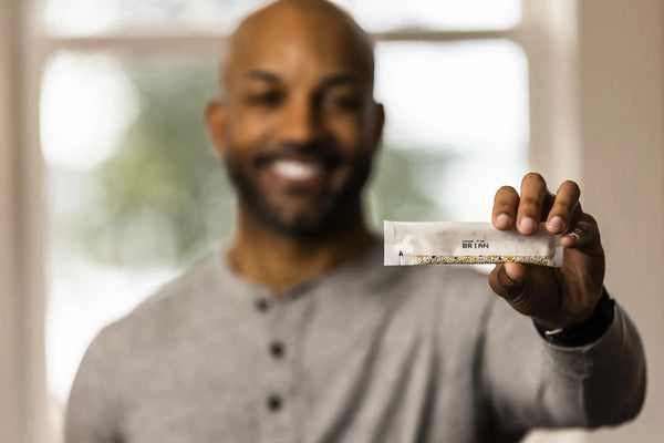 Brian smiling holding Rootine's Smart Multivitamin packet