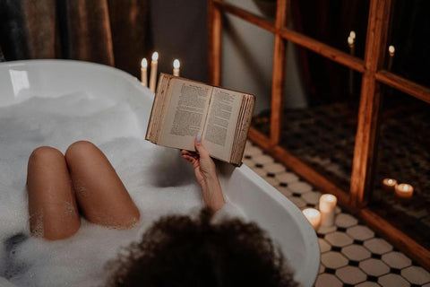 woman relaxing in bathtub with a book