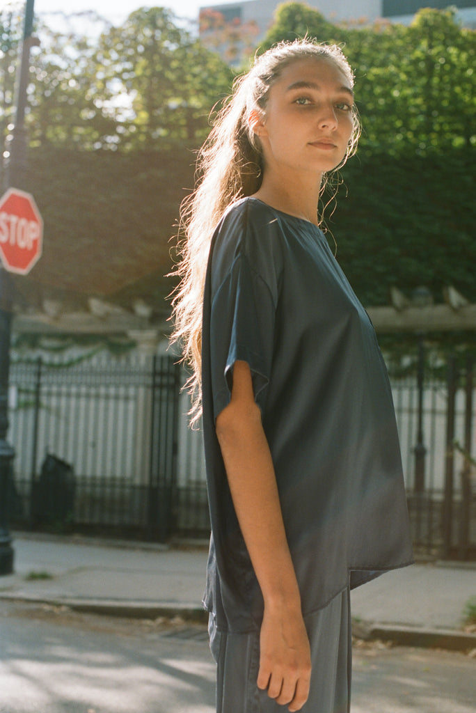 A woman wearing a blue silk t-shirt and pants.