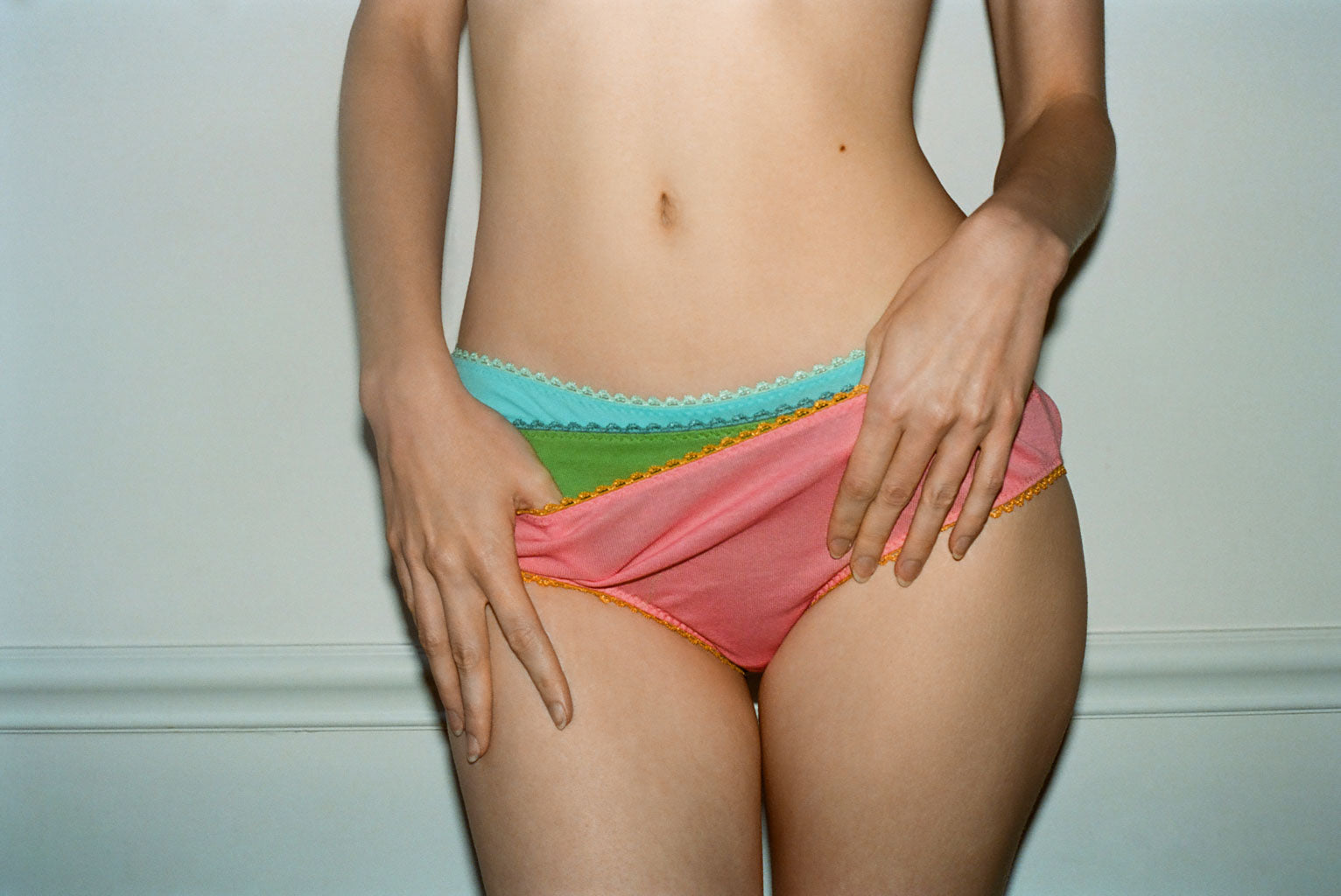 A model wearing three pairs of Isabella Panties in pink, green and blue.