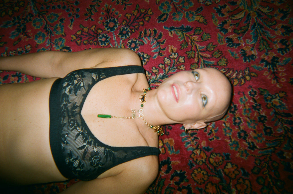 Woman in a black lace bra laying on a red carpet.