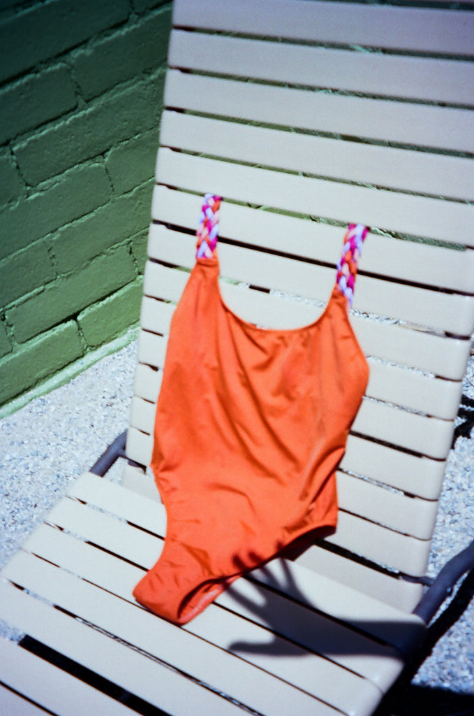 One Piece orange swimsuit with bright braided straps. 