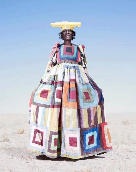 Tribal woman with a yellow hat and a multicolor square patterned dress.