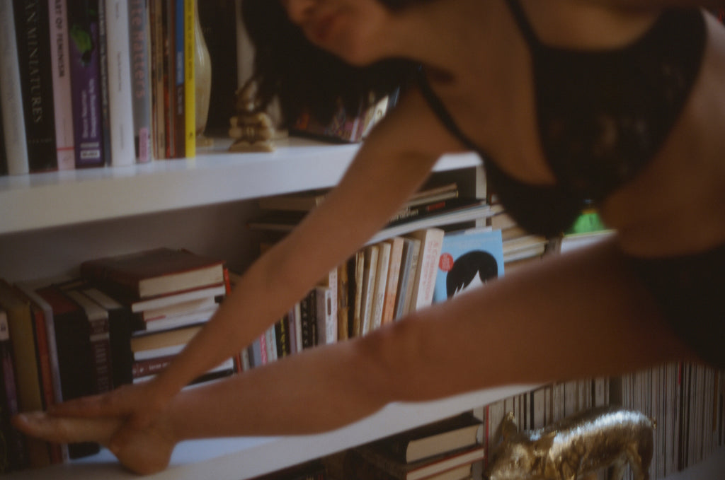 Araks wearing black lace underwear and bra by a book shelf.
