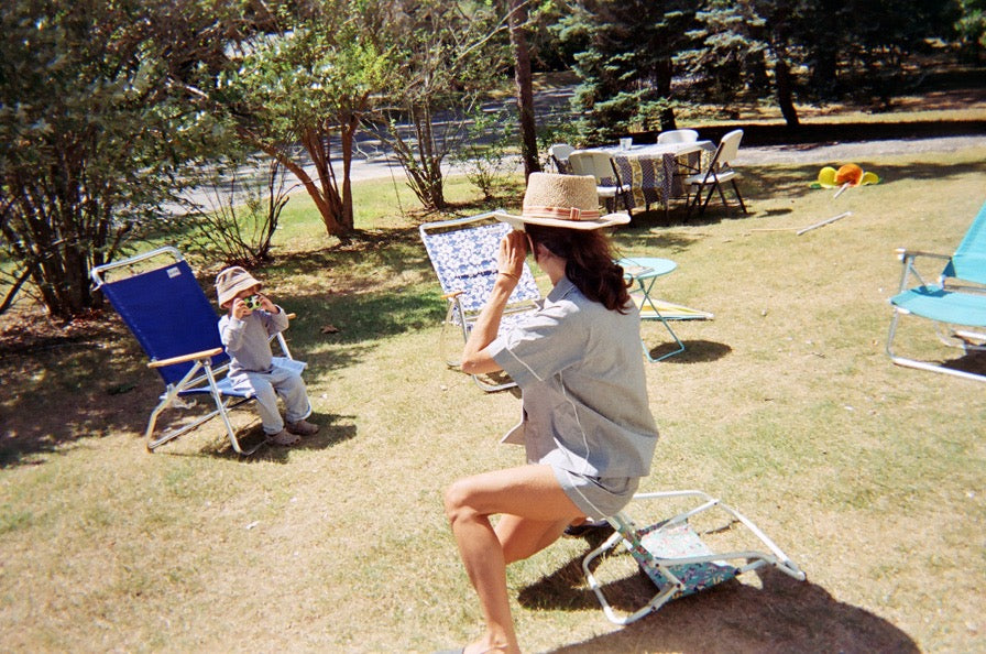 A mother and son taking photos of one another in a yard.