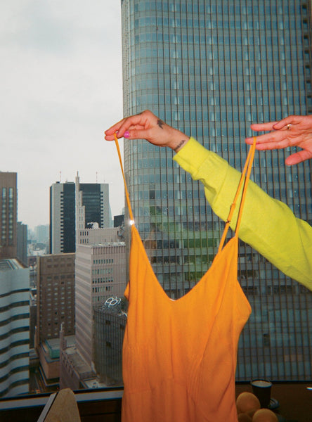 Orange chemise being held over a city scape.