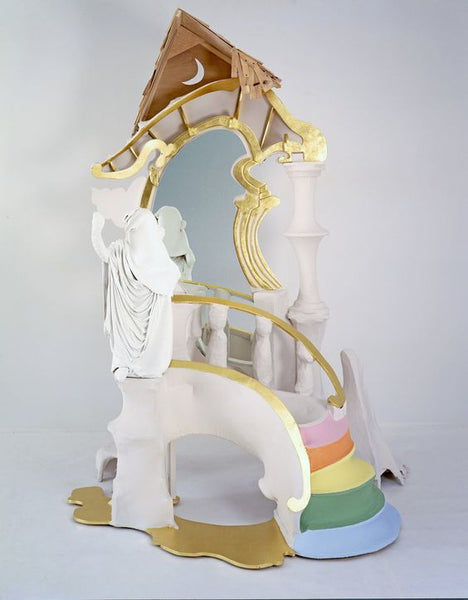 White sculpture with gold pieces and pink, orange, yellow, green steps.