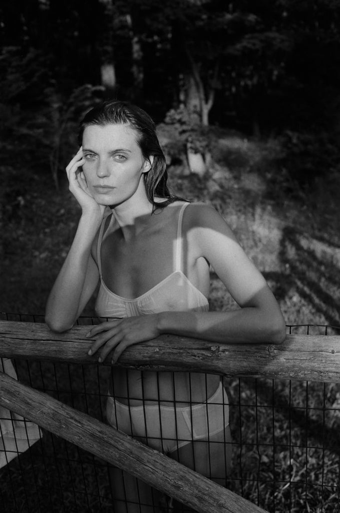 woman leaning on fence wearing white bra and panty