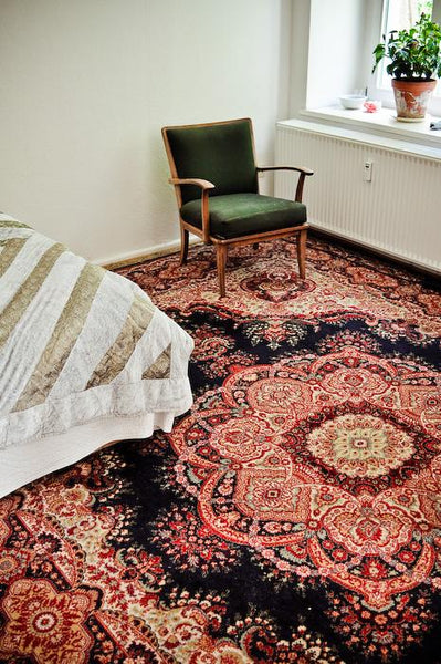 Blue and red oriental rug with a green chair sitting on it.