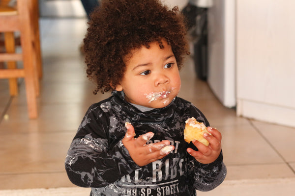 toddler in black and white long sleeve shirt eating yellow fruit