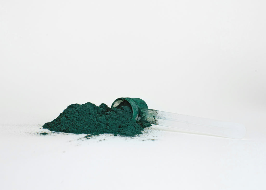 a scoop of green powder on a white surface