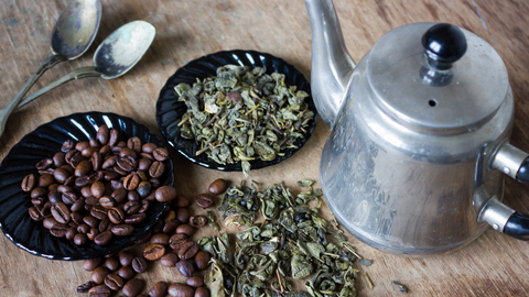 Coffee beand and dried green barley next to a silver kettle