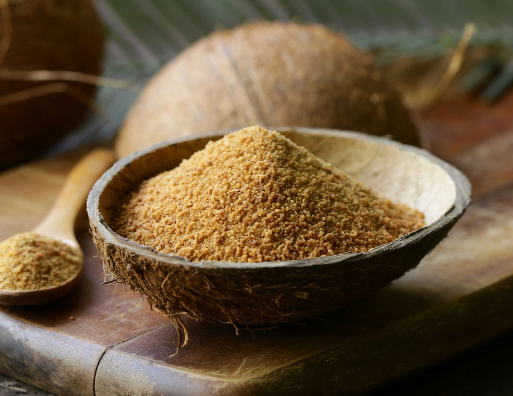 Brown coconut sugar fills half a coconut shell used as a bowl.