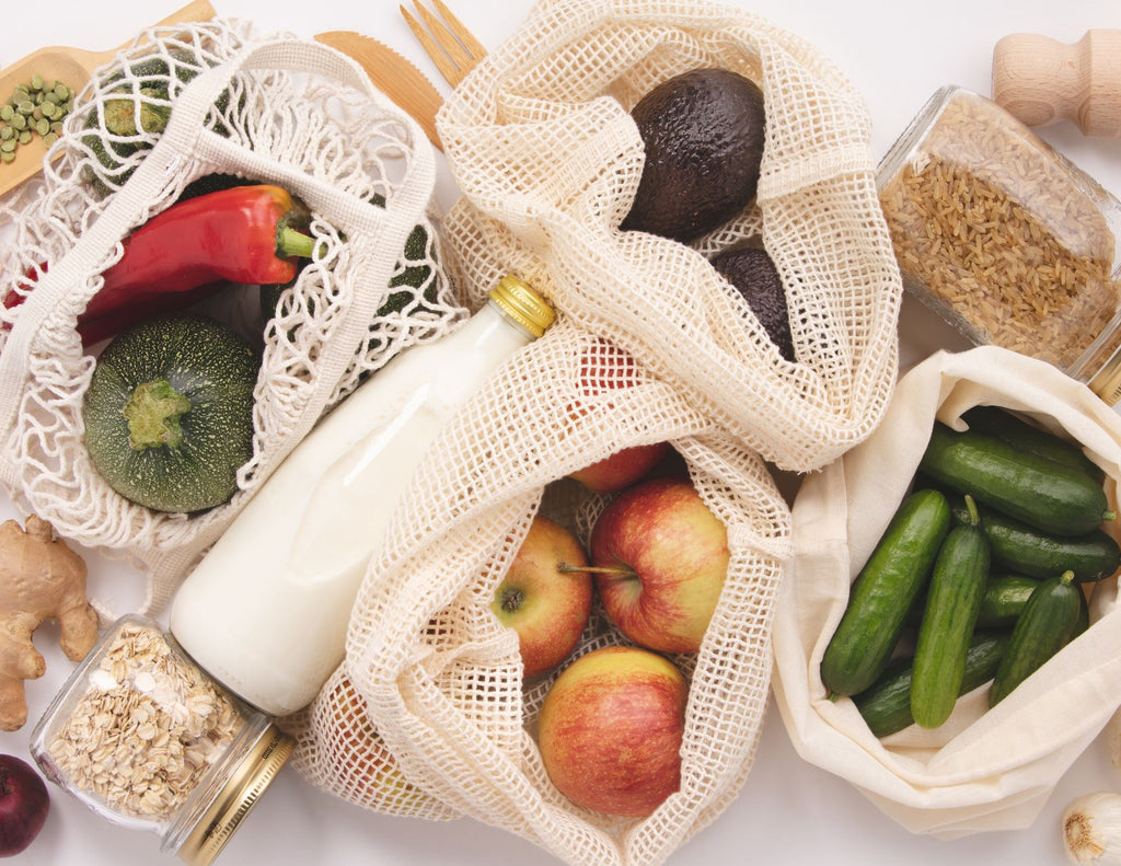Net-woven bags filled with vegetables with jars of grains and wood untensils.